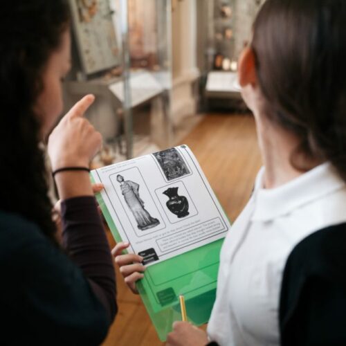 adult female and young female school child looking at activities on a clipboard in the gallery