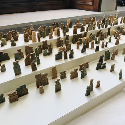 A display case with levels showing manay mini eye idols created by the artist Issam Kourbaj craved from Syrian Soap