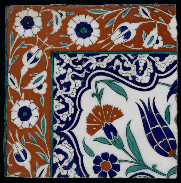 An Islamic Iznik tile with red green and blue decoration of natural forms