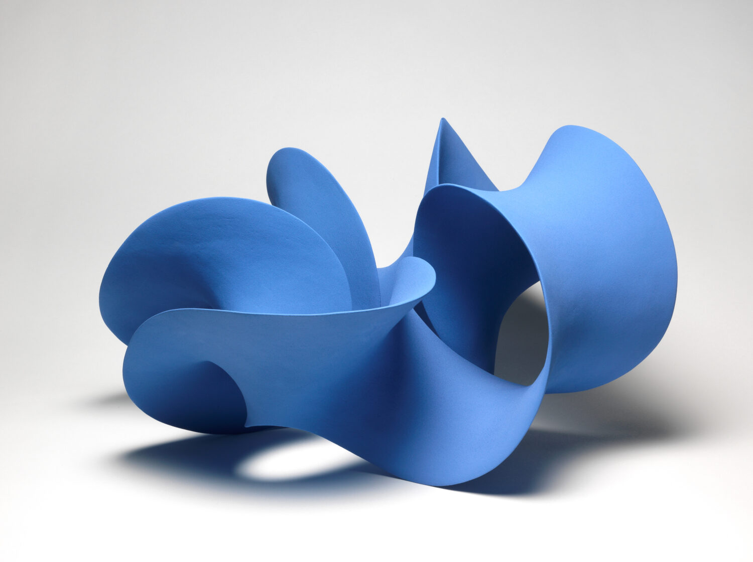 A photograph of a blue sculpture which twists and turns around in a circle. It is a mobius strip.