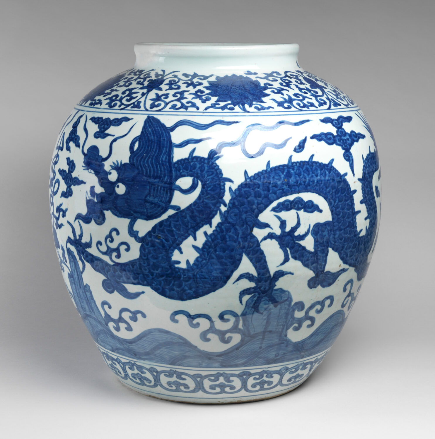 A large porcelain Chinese jar with blue decorations showing a dragon with a long body in the sky.