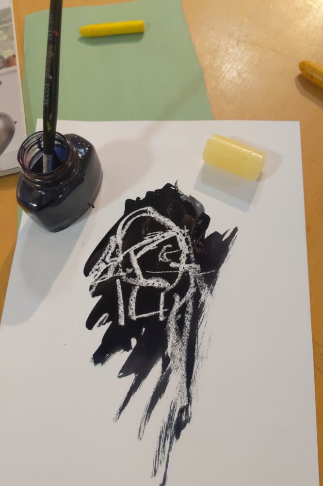 a wax drawing of a figure, painted over in ink to make them visible.
