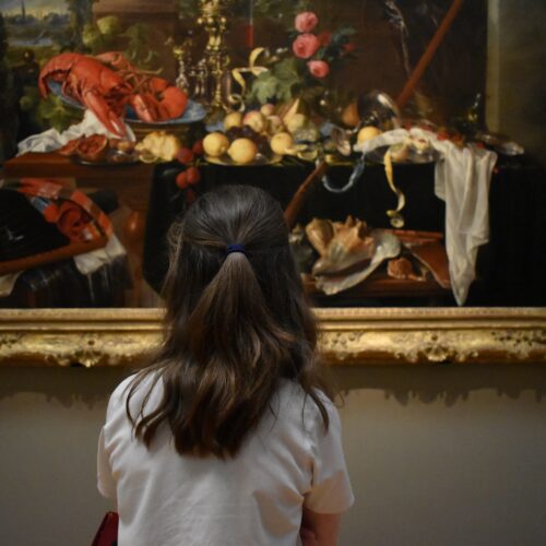 A pupil looks at a large painting of a banquet.